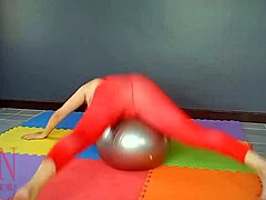 Regina Noir, o femeie matură, practică yoga într-o sală de gimnastică în timp ce poartă un dres roșu, chiloți de yoga și este rasă