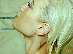 La beauté blonde montre son physique séduisant dans une scène de douche